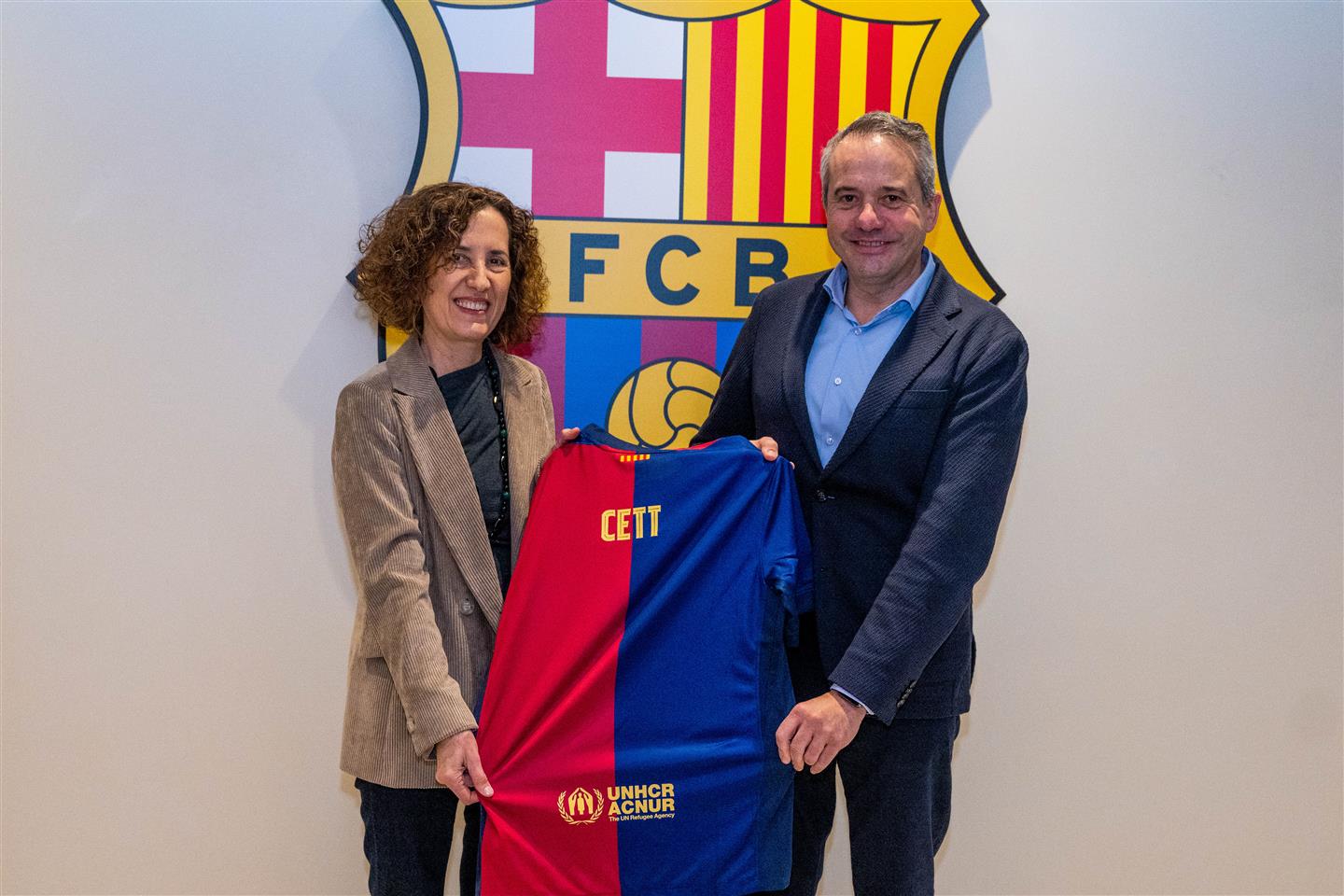 La Dra. Maria Abellanet i el Sr. Àngel Riudalbas posant amb una samarreta del Barça amb el nom CETT davant de l'escut del Barça.